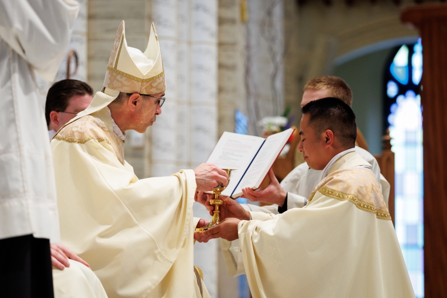Bishop James Ruggieri hands Father Nguyen a chalice.
