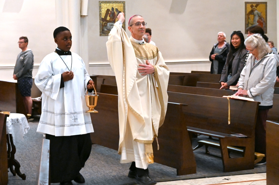 Bishop Ruggieri blessing sprinkling parishioners with holy water.