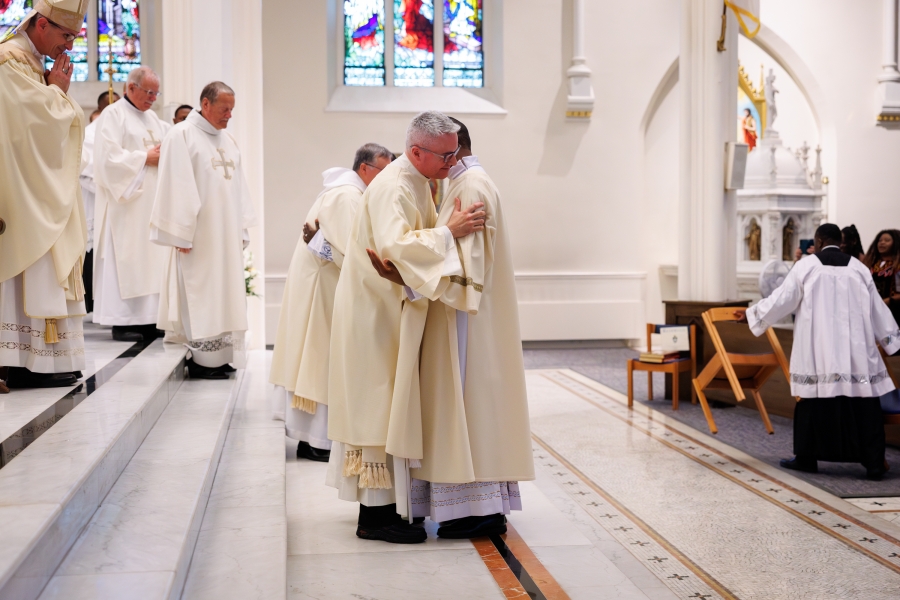 Deacon Banla receives the fraternal kiss of peace ( a hug) from Deacon Luis Sanclemente.