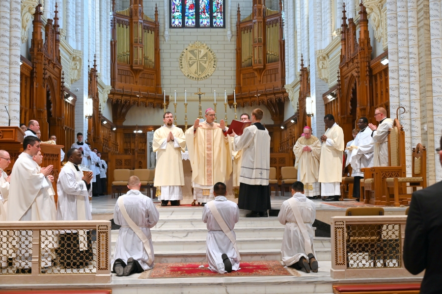 Bishop Ruggieri prays the Prayer of Ordination while the three ordinands kneel in front of him.