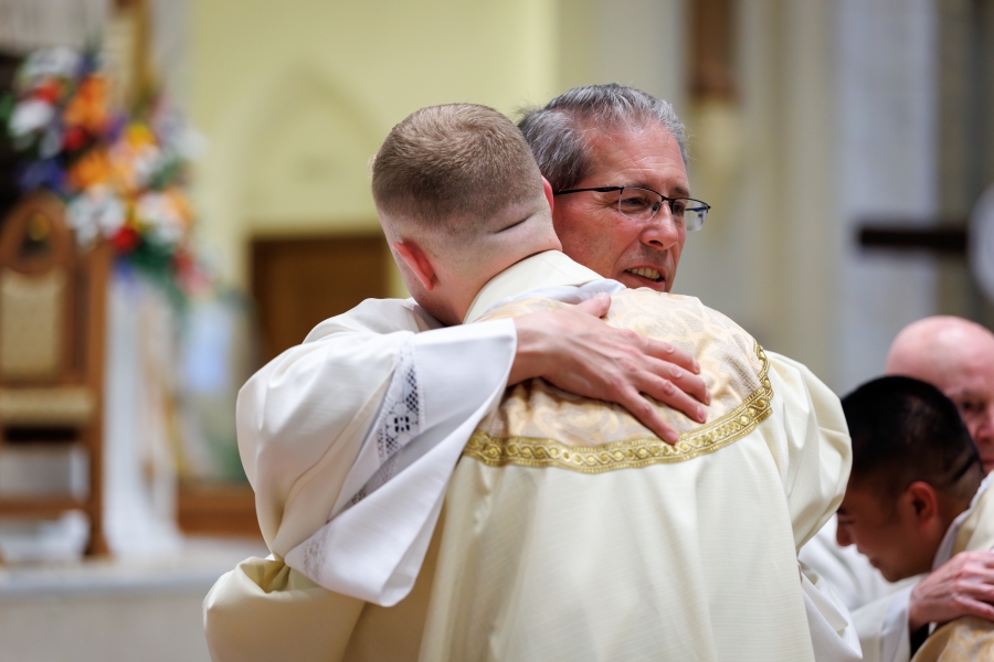 Father Robert Lupo offers the Fraternal Kiss of Peace to Father Erin Donlon.