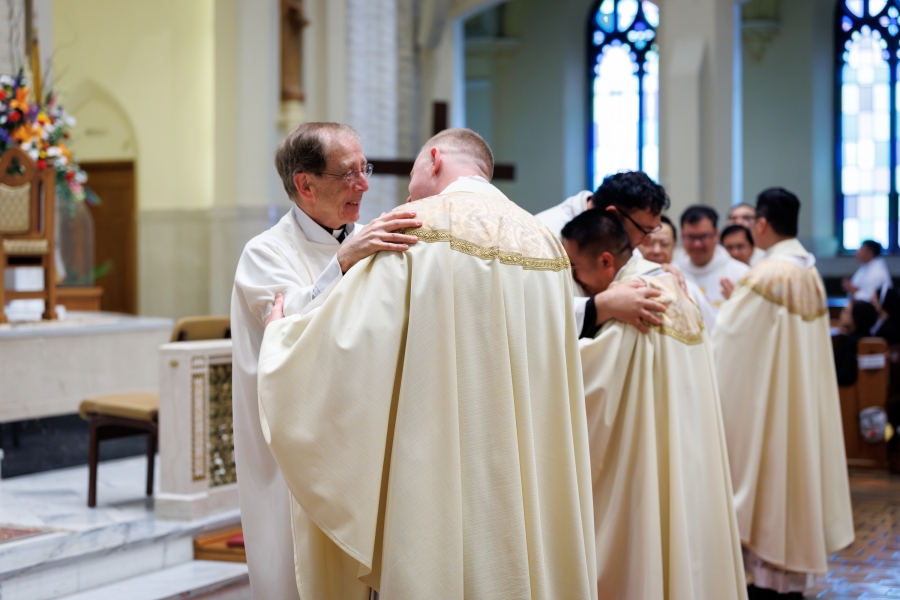 Father Dave Raymond offers the Fraternal Kiss of Peace to Father Erin Donlon.