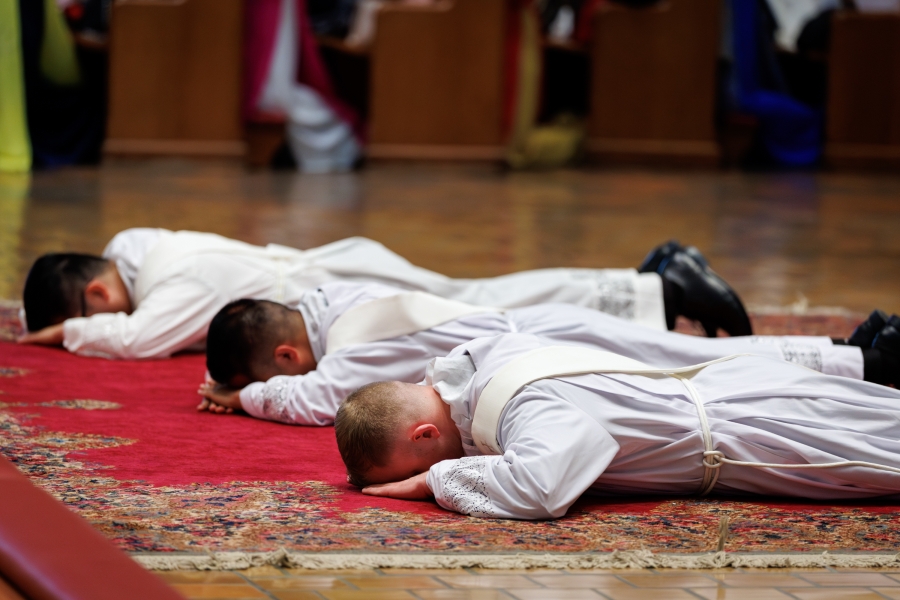 Three ordinands lie prostrate.