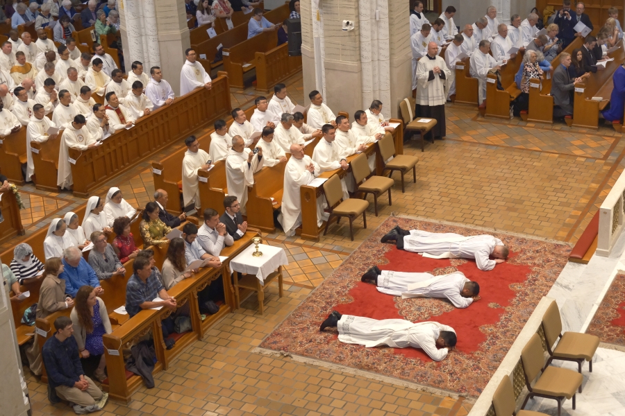 Three ordinands lie prostrate as seen from the balcony