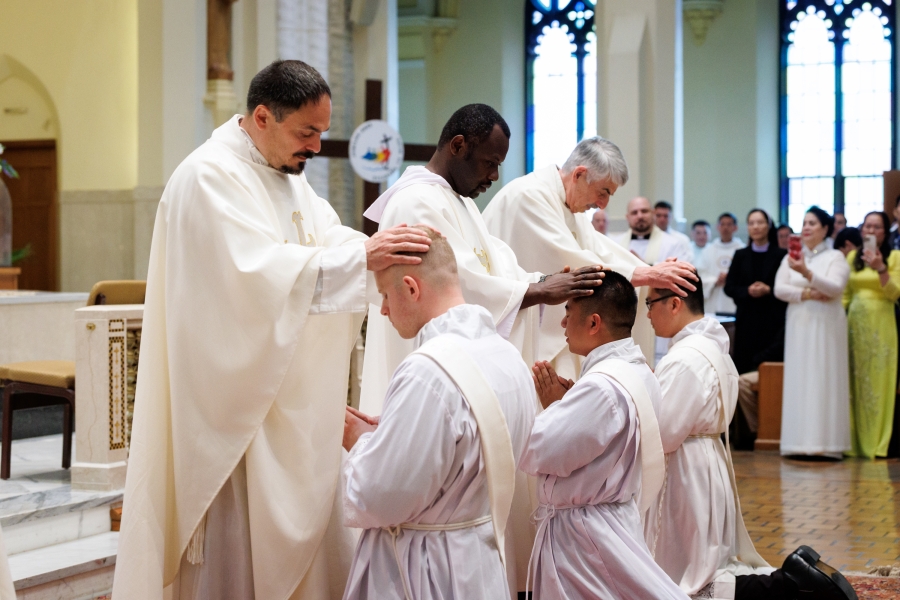 Priests lay hands on the ordinands.