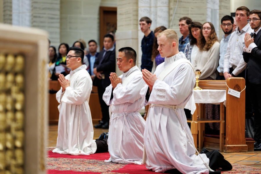Three ordinands kneeling.