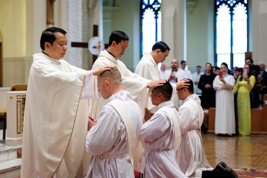 Priests lay hands on the ordinands.