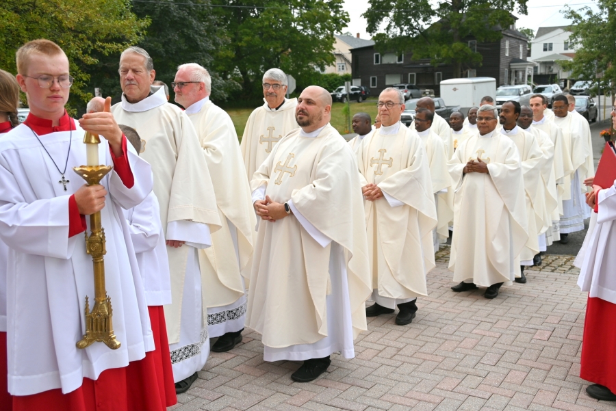Priests outside the church wearing cream vestments