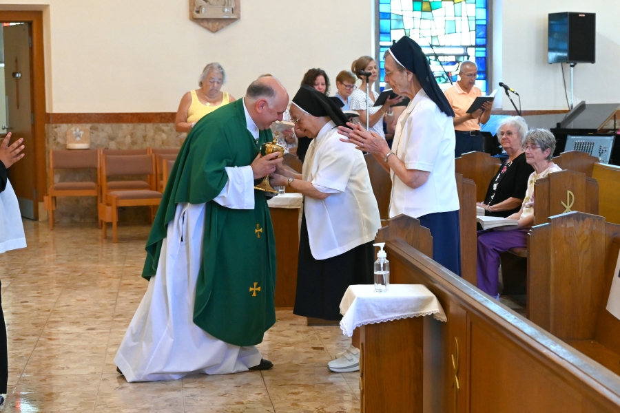 Sister Cecile Mondor and Sister Marie May Lausier present the gifts to Father Daniel Greeleaf.