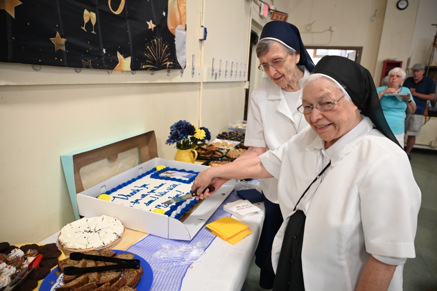 Sister Marie May and Sister Cecile cut a cake.