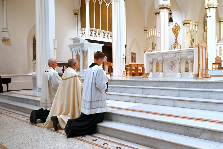 Bishop Ruggieri, Father Seamus Griesbach, and an altar server kneel before the Blessed Sacrament.