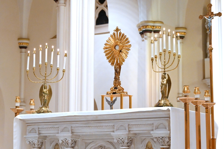 The Eucharist in a monstrance with candles on either side.