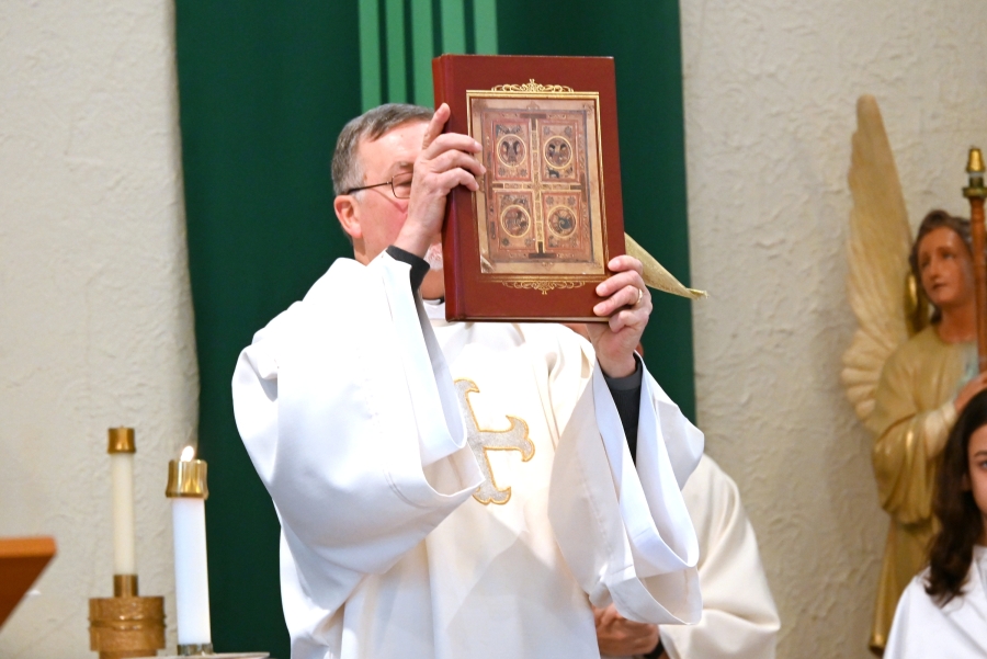 Deacon Peter Bernier holds up the Book of the Gospels.