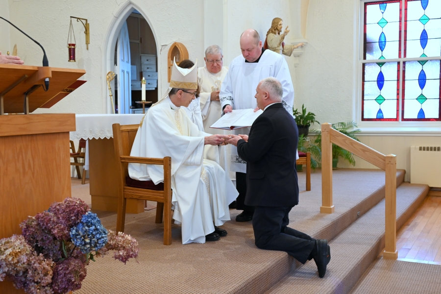 Adam Stearns kneels before Bishop Ruggieri.
