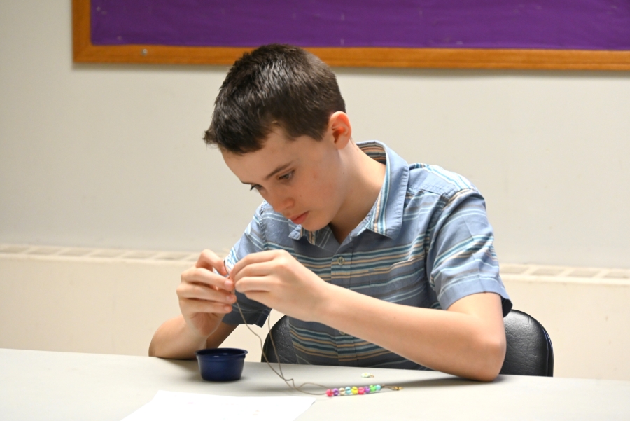 Boy making rosary beads.