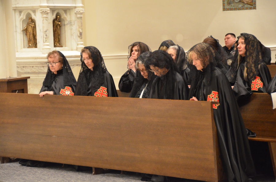Woman in black kneeling in the pew.