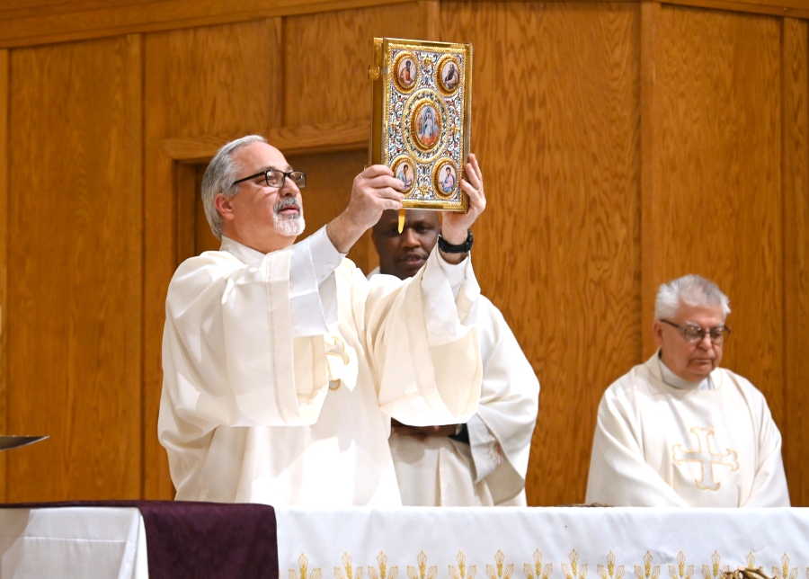 Deacon Rodney Deschaine holds up the Book of the Gospels