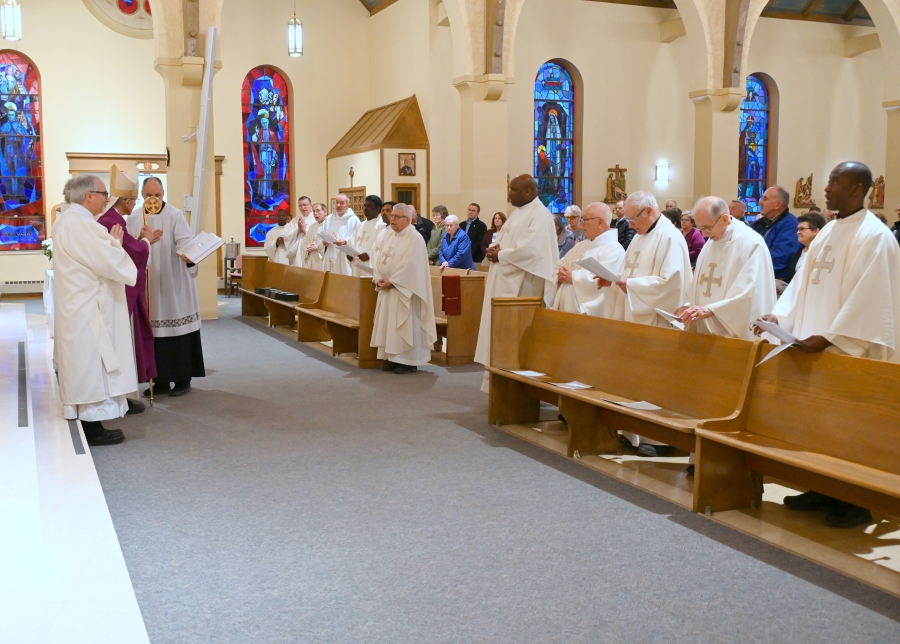 Priests stand before the bishop to renew their vows.
