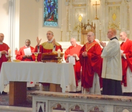 Bishop Ruggieri, Bishop Deeley, and priests at the alter in red vestments