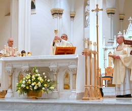 Bishop James Ruggieri holds up the chalice, surrounded by other priests.