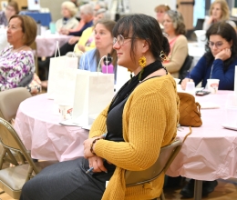 Woman wearing a gold sweater sitting at a table.