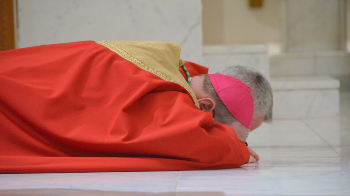 Bishop Deeley lies prostrate.