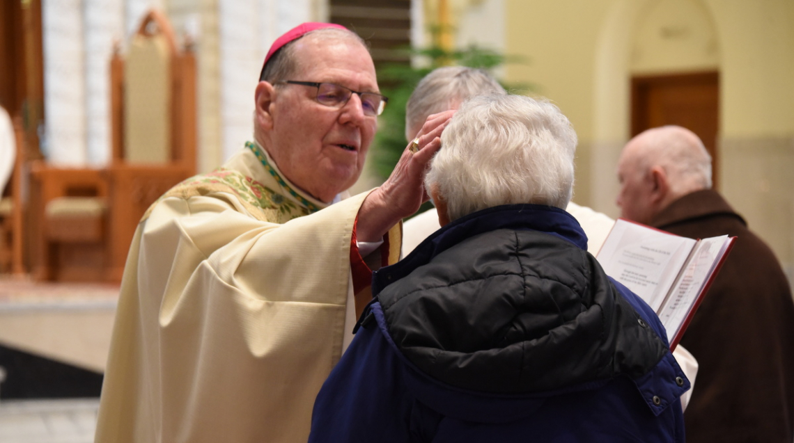 Bishop Deeley anoints the forehead of a woman.