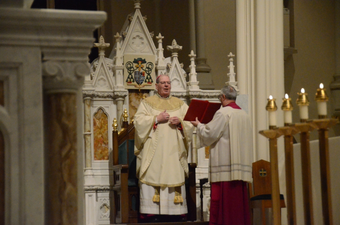 The bishop reads from a book from the altar