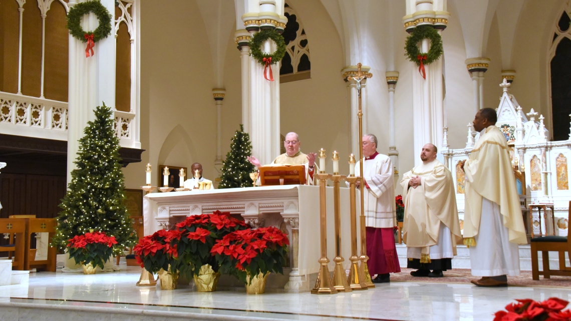 Bishop Deeley celebrating the Liturgy of the Eucharist with several priests beside him.