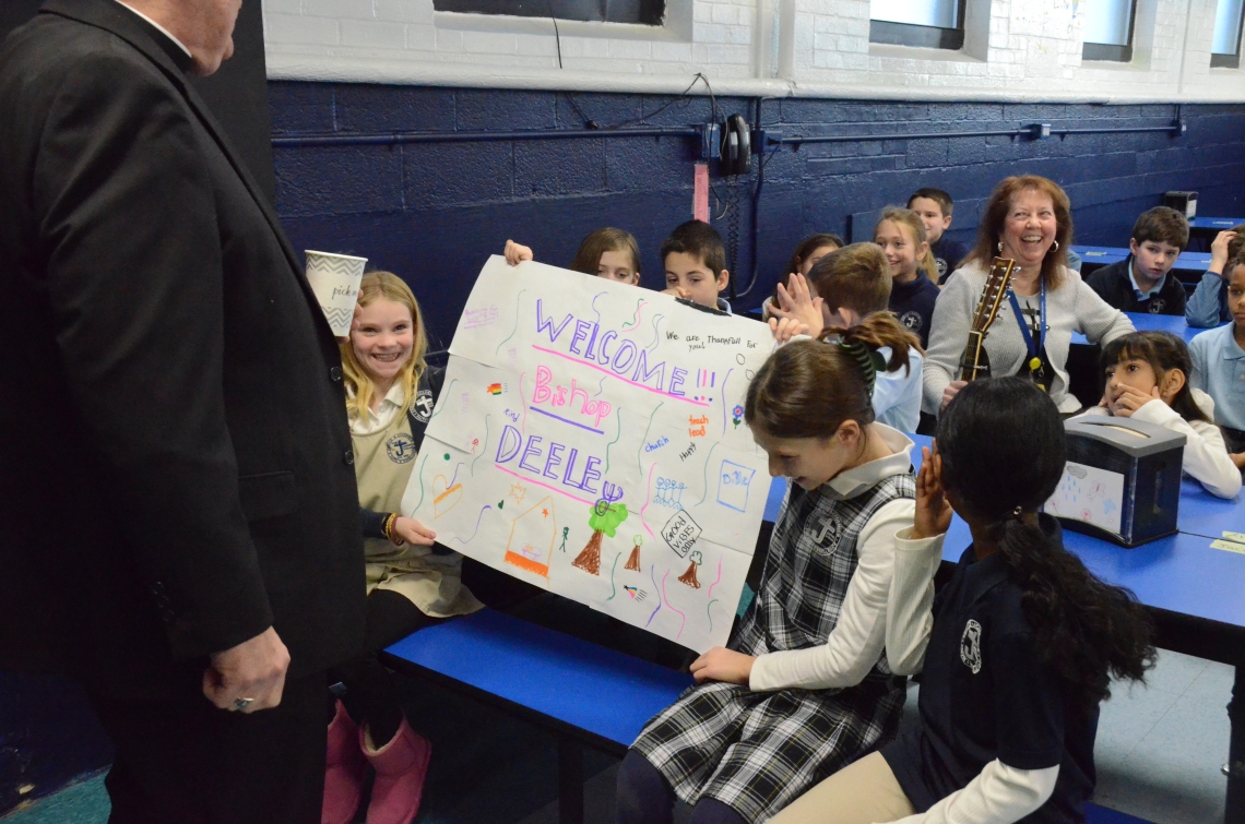 two students hold up a sign for the bishop