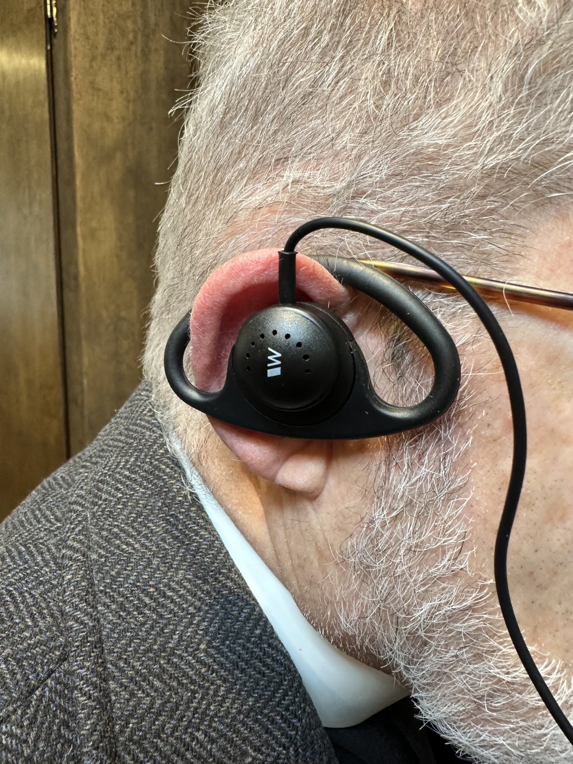 man wearing listening assist device in ear