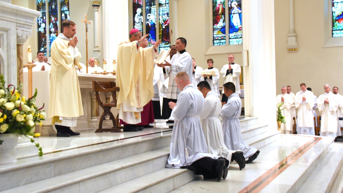 Bishop James Ruggieri prays the Prayer of Ordination for Hoa Tien Nguyen, Thanh Duc Pham, and Erin Donlon.