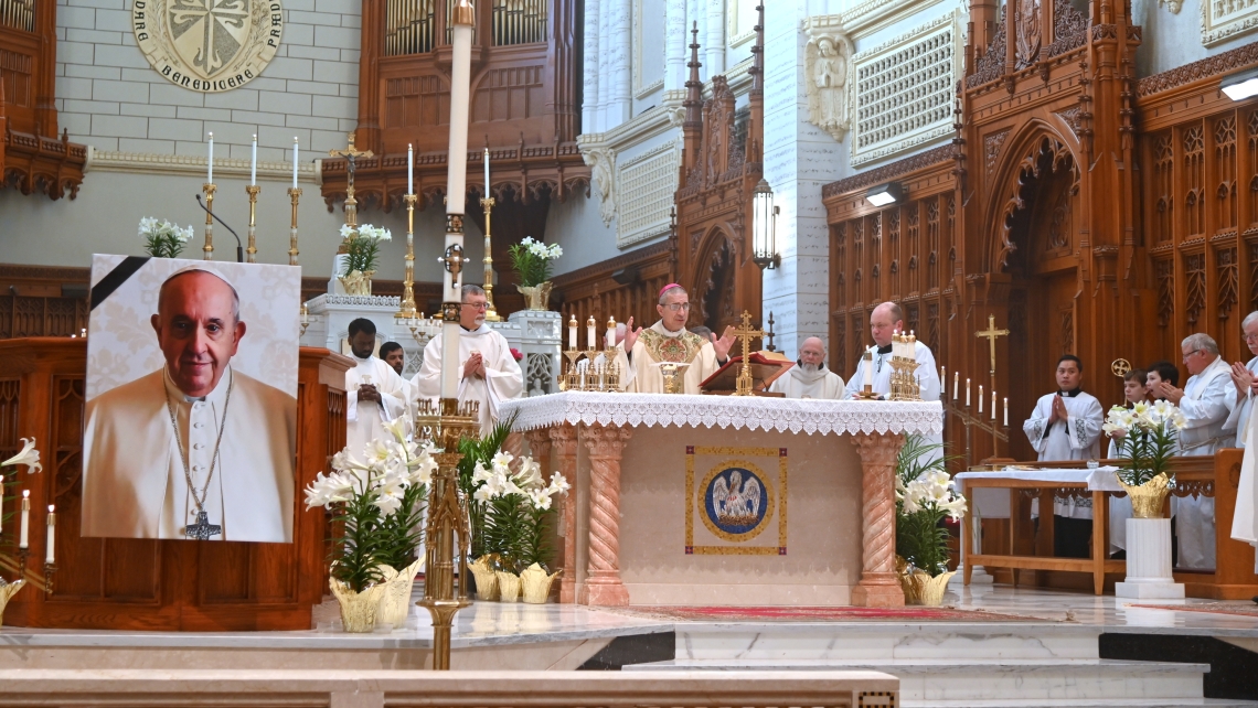 Bishop James Ruggieri at the altar during the Liturgy of the Eucharist. A picture of Pope Francis is in the foreground in front of the abmo.