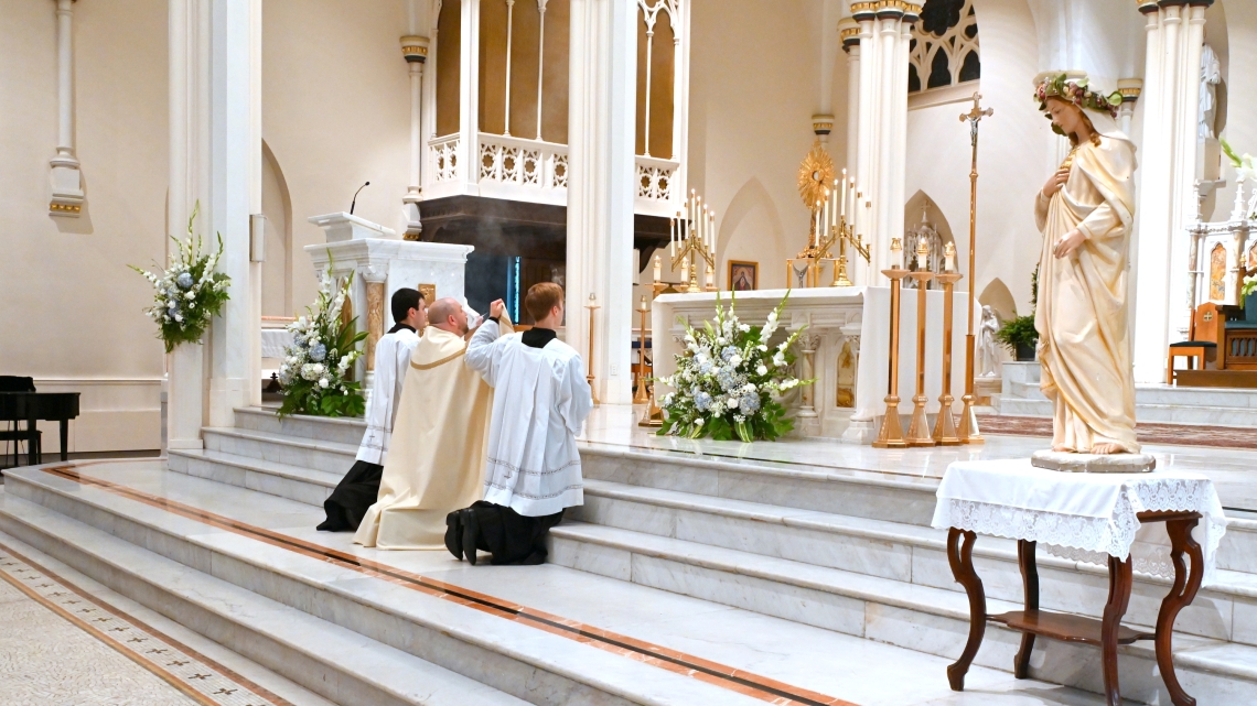 Father Brad Morin and two altar servers incensing the Blessed Sacrament.