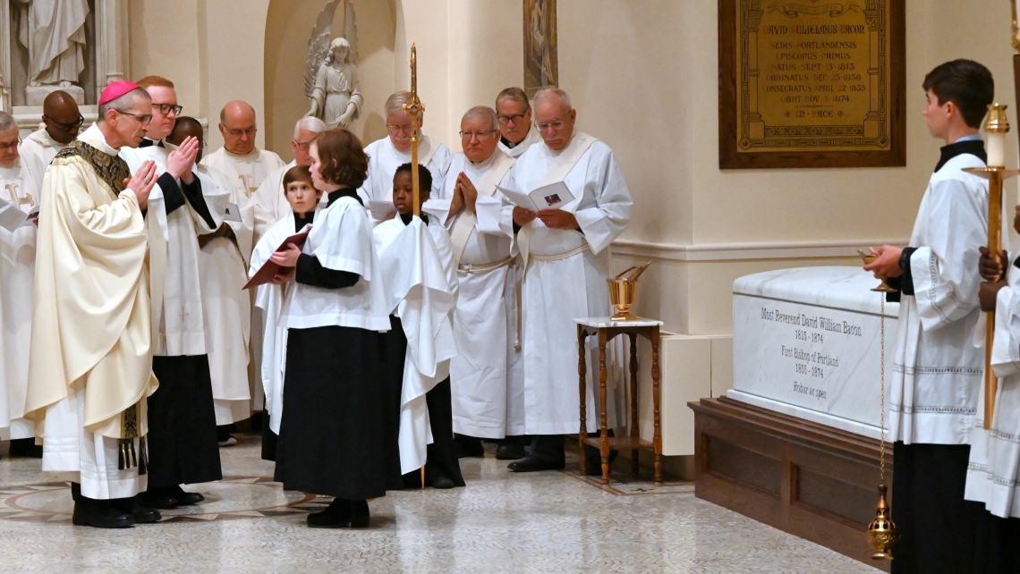 Bishop James Ruggieri, surrounded by priests and deacons, blesses the tomb of Bishop David Bacon.