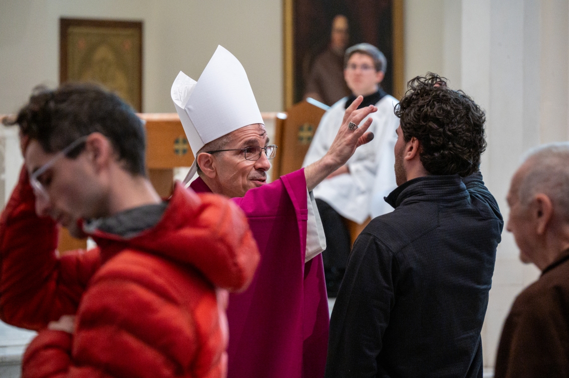 Bishop Ruggieri applies ashes to a young man's forehead