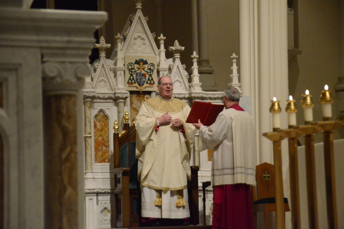 The bishop reads from a book from the altar