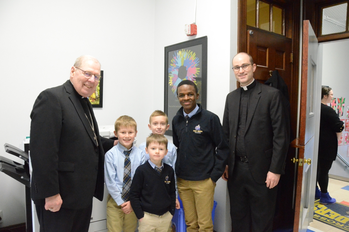 The bishop and a priest pose with three Catholic school students
