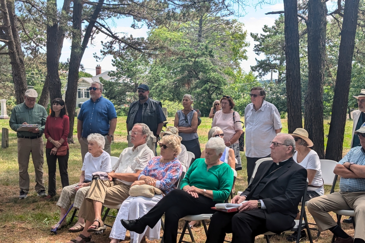 Group sits in a wooded cemetery.