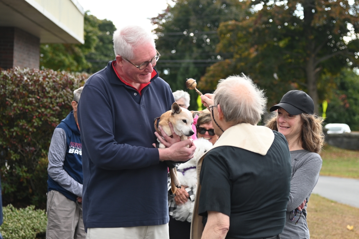 Father Michalowski sprinkles a dog with holy water.