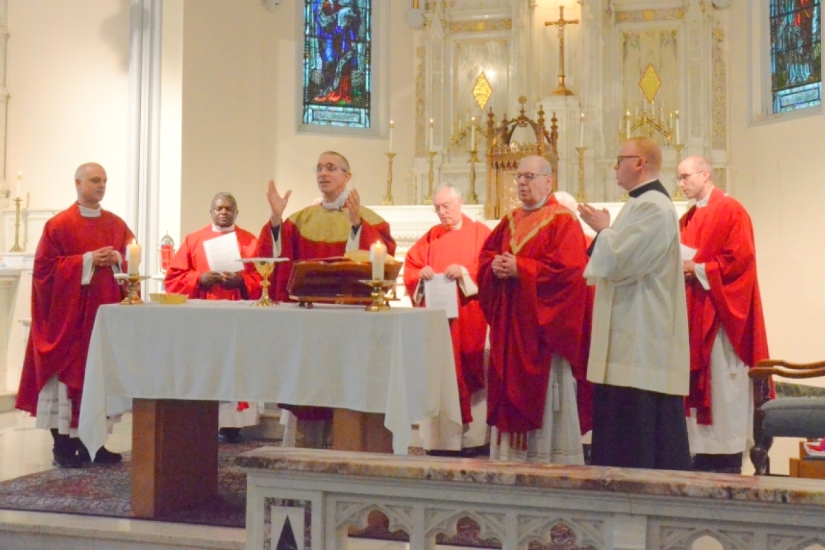 Bishop Ruggieri, Bishop Deeley, and priests at the alter in red vestments