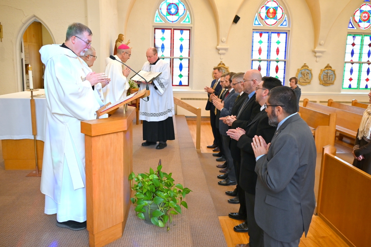 Deacon candidates stand before Bishop Ruggieri with Deacon Peter Bernier in the foreground