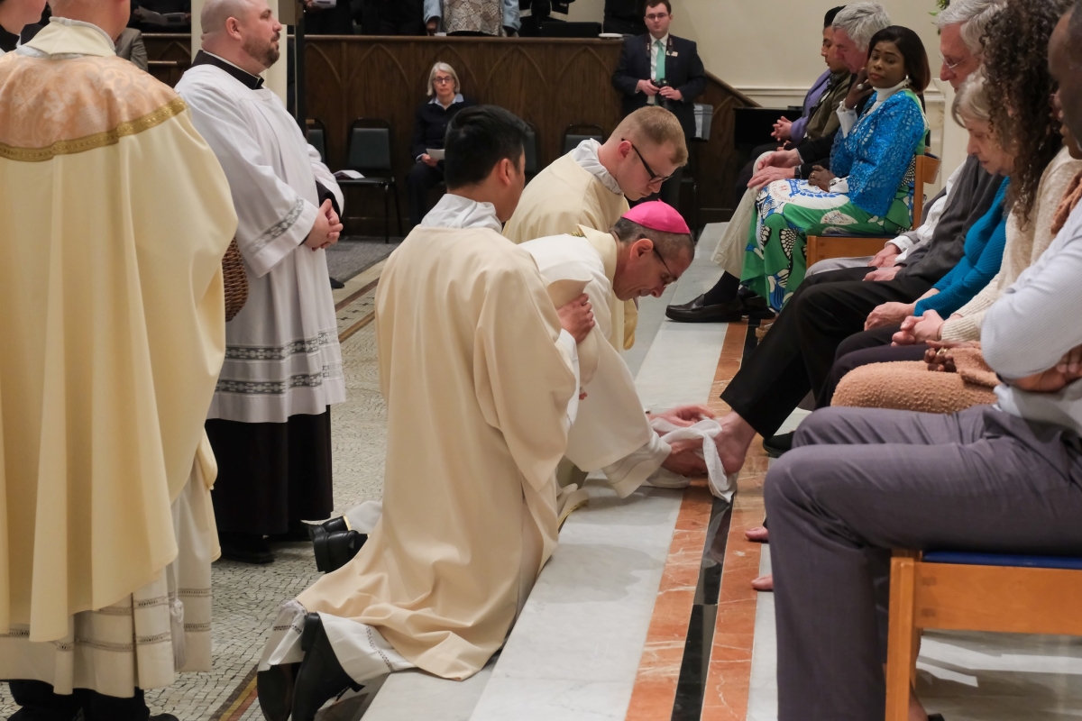 Bishop kneeling and washing feet on the altar.
