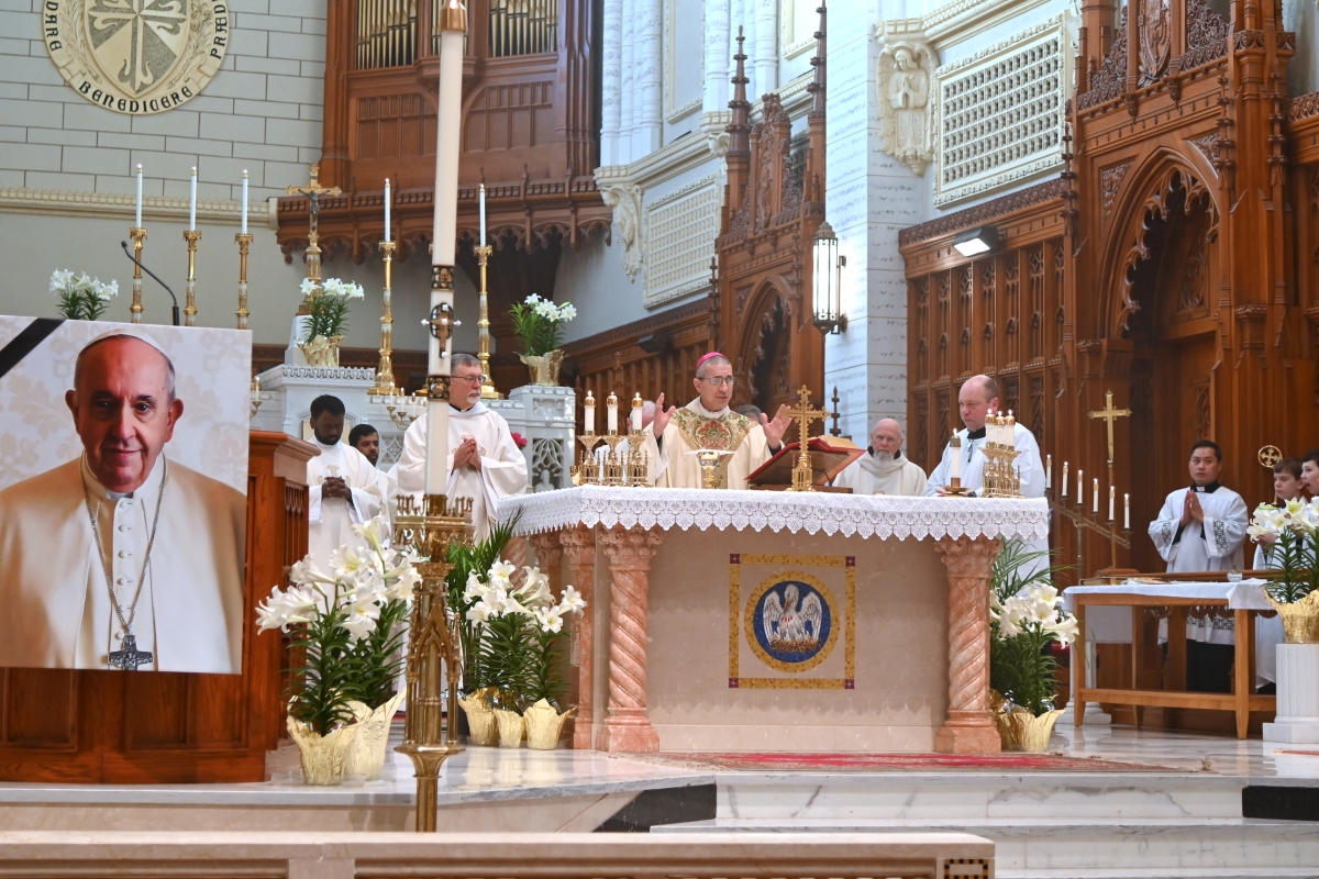 Bishop James Ruggieri at the altar during the Liturgy of the Eucharist. A picture of Pope Francis is in the foreground in front of the abmo.