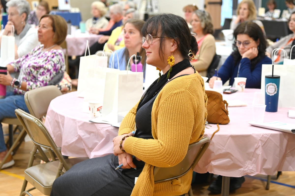 Woman wearing a gold sweater sitting at a table.