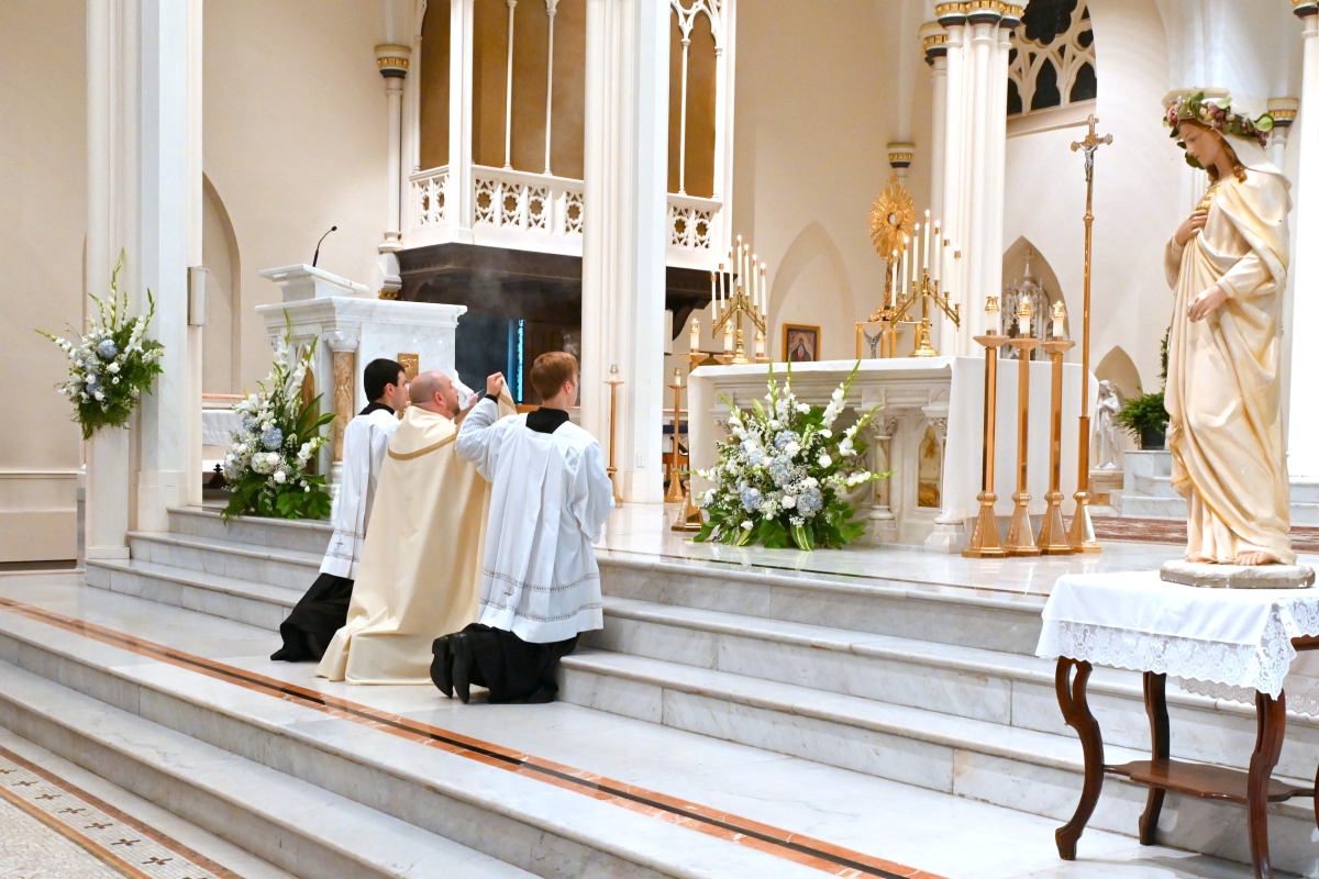 Father Brad Morin and two altar servers incensing the Blessed Sacrament.