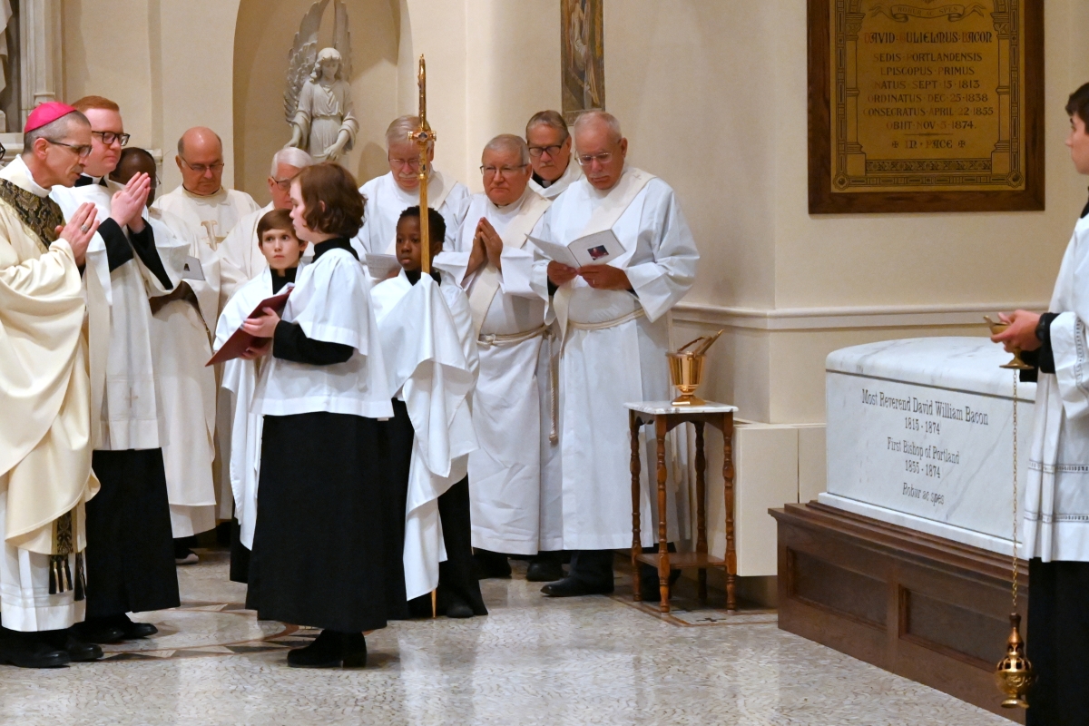 Bishop James Ruggieri, surrounded by priests and deacons, blesses the tomb of Bishop David Bacon.