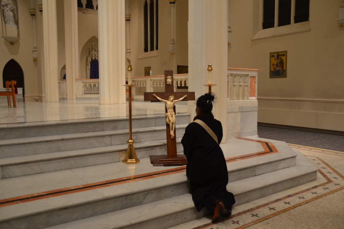 Woman kneels in from of the cross